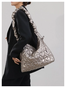 Detail of heart quilted tote bag with metallic sheen and pleated shoulder strap on model