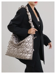 Detail of silver quilted heart pattern shoulder bag with ruched handle on black blazer