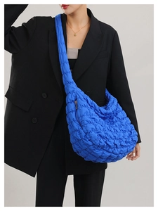 Close-up of vibrant blue quilted nylon crossbody bag with textured cloud pattern detail