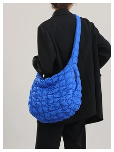Quilted blue cloud crossbody bag detail showing large capacity on model in black blazer