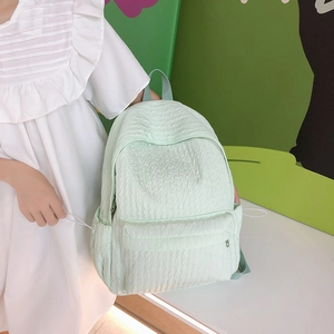 Sac à dos vert menthe à texture ondulée et poches latérales tenu par un mannequin