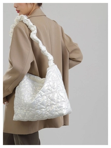 Detail of white heart-quilted puffer tote bag with decorative ruffled shoulder strap