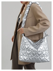 Silver heart quilted shoulder bag with metallic texture and pleated wide strap on a model