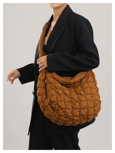 Detailed view of the brown quilted crossbody cloud bag showing oversized design and texture