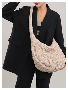 Close-up of beige quilted cloud bag with gold zipper and textured puffer fabric detail