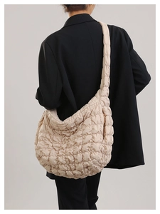 Detail of beige quilted cloud bag with rhombus stitching texture on crossbody strap