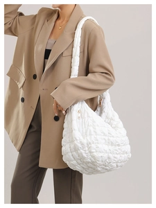 Side view of a white quilted puffer shoulder bag showing lightweight puffy texture