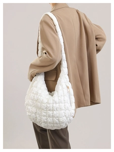 Close-up of white quilted puffer bag with cloud texture and gold zipper detail