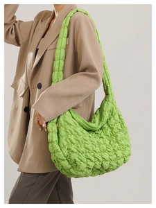 Fashionable green quilted cloud bag with hobo silhouette on a stylish model