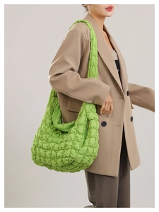 Detail of green quilted puffer shoulder bag with soft textured nylon and zipper closure
