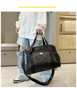 Dettaglio della borsa da viaggio grande nera con trama a coccodrillo e tracolla