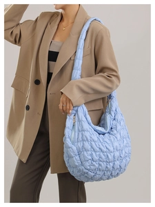 Light blue quilted puffer bag with wide strap shown on a model for casual daily use