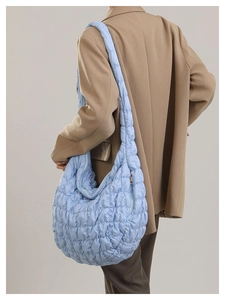 Detail of light blue quilted cloud shoulder bag with sleek metal zipper and textured fabric