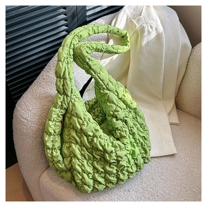Detailed close-up of light green quilted hobo bag with puffy cloud-like texture and wide strap