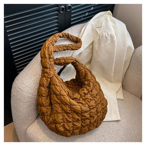 Detailed texture of brown quilted cloud crossbody bag on a white textured sofa