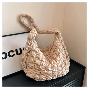 Detail view of the quilted texture and golden zipper on the beige cloud crossbody bag