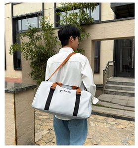 Gran bolsa de viaje gris con asas marrones y correa ajustable en una toma exterior