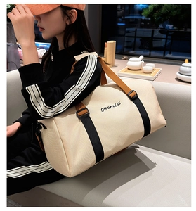 Bolsa de viaje beige de gran capacidad con correas naranjas llevada por modelo