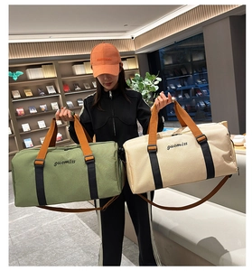 Detalle de bolsos de viaje de lona oliva y beige con asas naranjas y correas largas