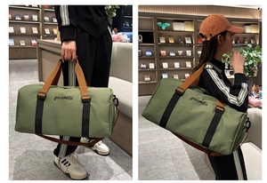 Detalle de bolsa de viaje verde militar con bordado negro y correa de hombro ajustable