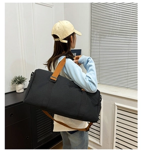 Detalle de bolsa de deporte de nailon negro con asas tejidas marrones en modelo femenina