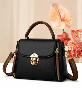 Close-up of black lychee grain leather handbag with brown straps and gold metal lock