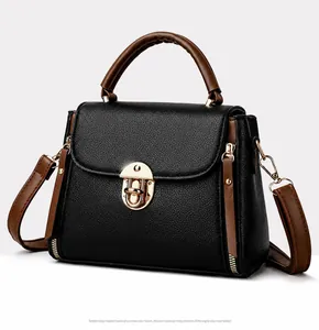 Side view of two-tone crossbody bag with black lychee leather and gold clasp detail