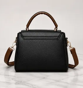 Detail view of the black pebble leather texture and brown handle on a crossbody bag