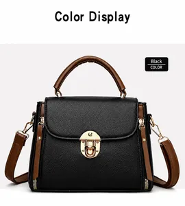 Detail of black pebbled leather handbag with brown handles and gold rotary buckle