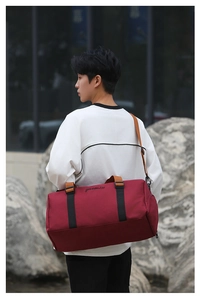 Man wearing dark red oxford travel tote bag with separate shoe compartment and shoulder strap