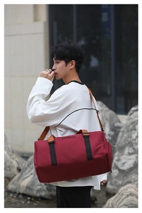 Detail of burgundy oxford gym bag featuring black straps and adjustable shoulder belt