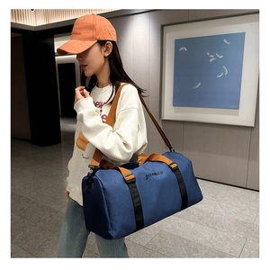 Model wearing a blue oxford travel tote bag with shoulder straps and reinforced black webbing