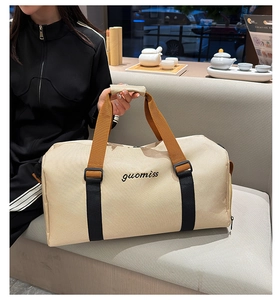 Close-up of a beige Oxford travel tote bag featuring black reinforced straps and brand logo