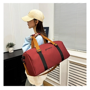 Modern burgundy oxford gym bag with reinforced straps held by a model in an indoor setting