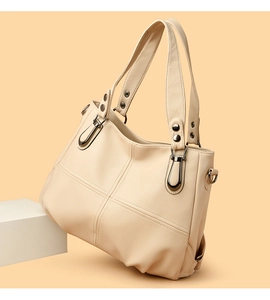 Detailansicht der cremefarbenen Ledertasche mit Kreuznähten und dunkler Metallschnalle