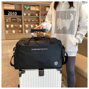 Detalle de la bolsa de viaje negra impermeable con asa retráctil sobre maleta a rayas
