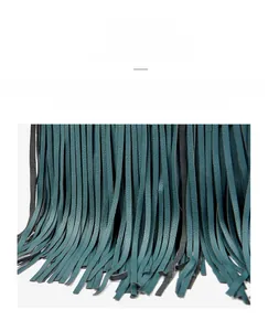 Dettaglio ravvicinato della pelle cerata color teal e delle frange decorative della borsa
