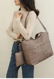 Detail view of large coffee brown PU leather tote bag with shoulder strap on model