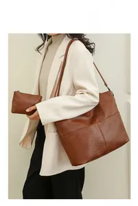 Brown vintage litchi grain leather tote and clutch set styled on a model in white blazer