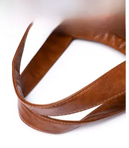 Close-up of brown leather bag handle with precise stitching and refined texture