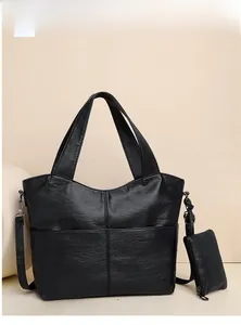 Detail of black pebbled leather tote bag with matching zippered pouch and crossbody strap