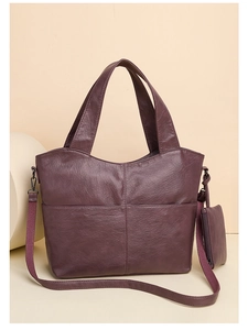Detail of dark purple faux leather tote bag featuring stitching and small coin purse