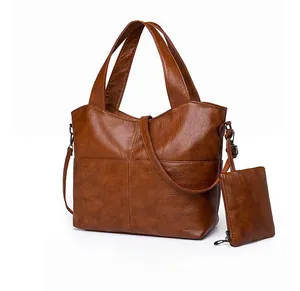 Close-up of brown textured leather tote bag showing small zipper pouch and long shoulder strap