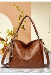 Close-up of brown leather bucket bag featuring V-shaped stitching and tassel detail