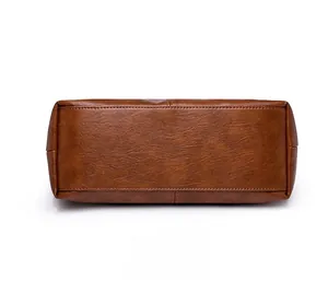 Detail view of the wide rectangular reinforced bottom of the brown leather handbag