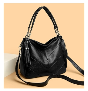 Detail of black leather tote bag with V-shaped stitching and decorative tassel