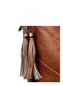 Macro detail of brown litchi grain leather bag featuring metal latch and double tassels