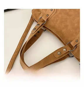 Detail view of brown frosted leather bag handle with metal rings and silver rivets