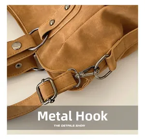 Detail of gunmetal hardware hooks and durable stitching on a camel suede shoulder bag