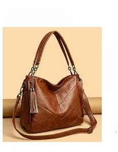 Close-up of brown textured leather bag with V-shaped stitching and tassel charm